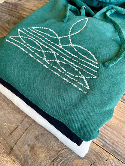 Green hoodie with white embroidered design on a wooden surface