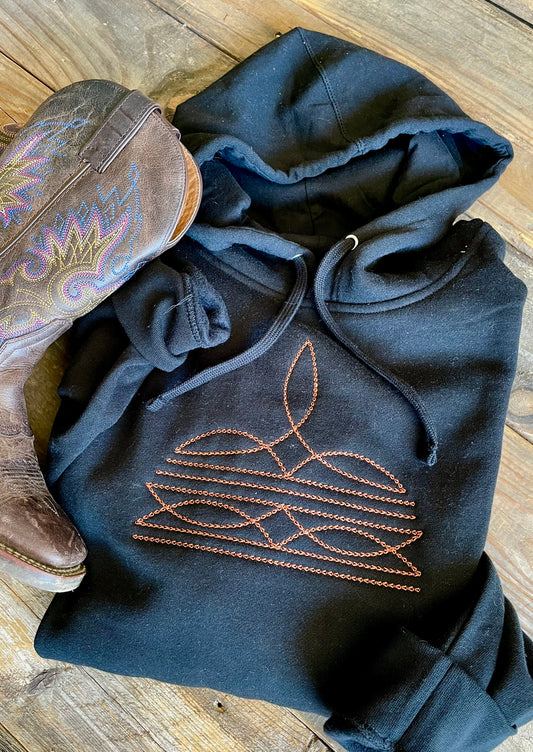 Black hoodie with embroidered design on a wooden surface
