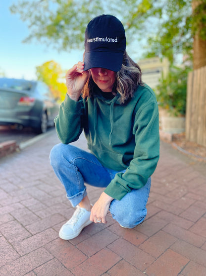overstimulated embroidered in white on a black dad hat